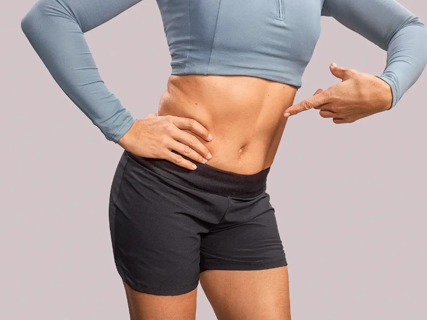 Mujer con camisa y saco con dolor agarrándose la panza